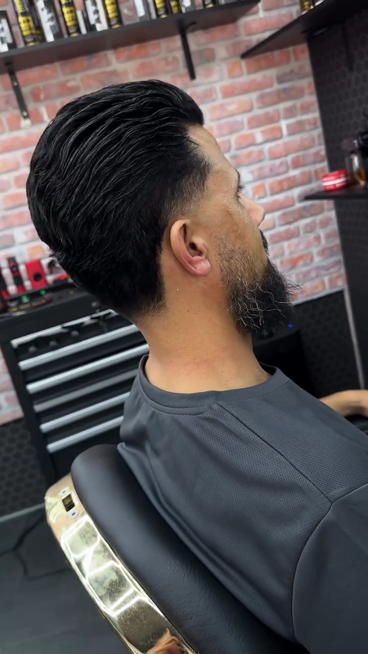 Zijprofiel van een slick back met een volle baard die in de fade overloopt