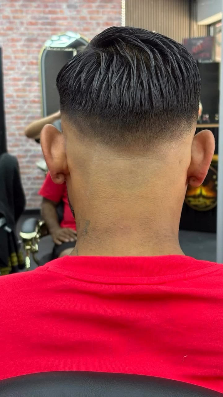 Achterhoofd met een skin fade, klant in een rood shirt